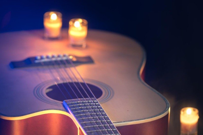 Acoustic guitar on a black background with candles