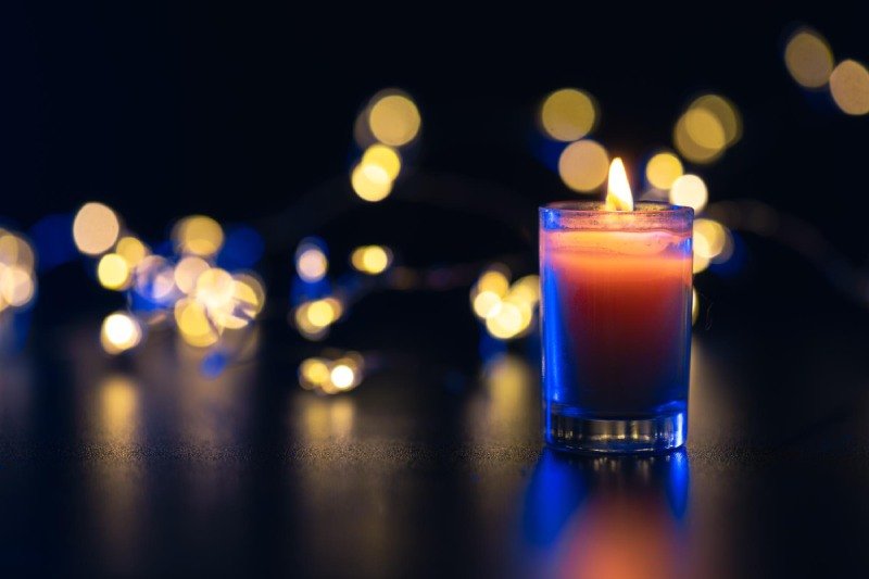 Burning candle on black background with bokeh memorial day
