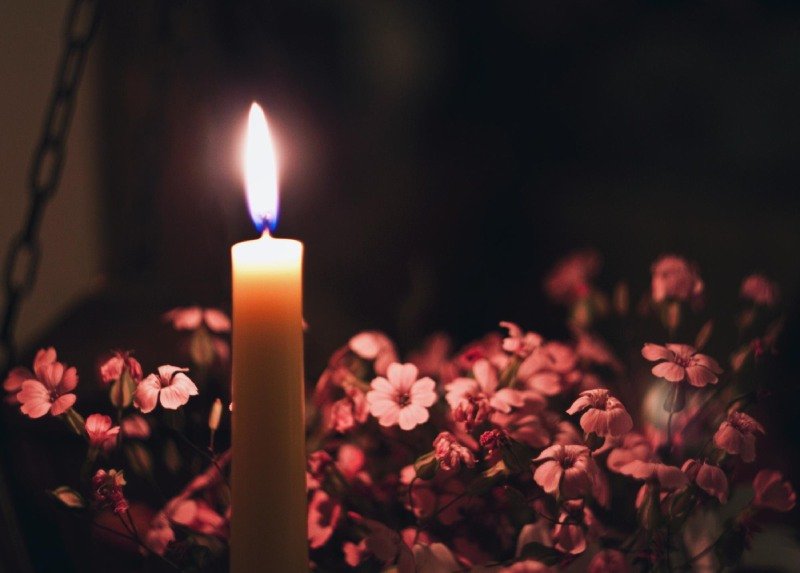 Close-up of lit candle by flowers