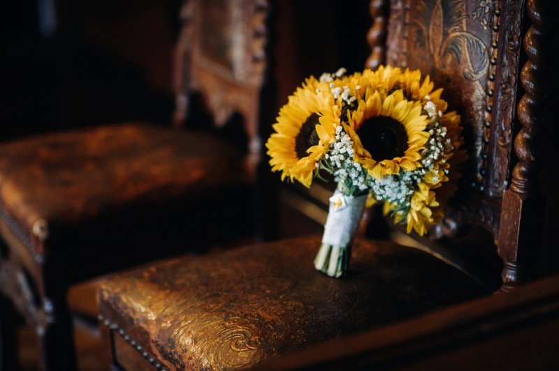 A wedding bouquet of sunflowers lies on an antique chairwedding decor